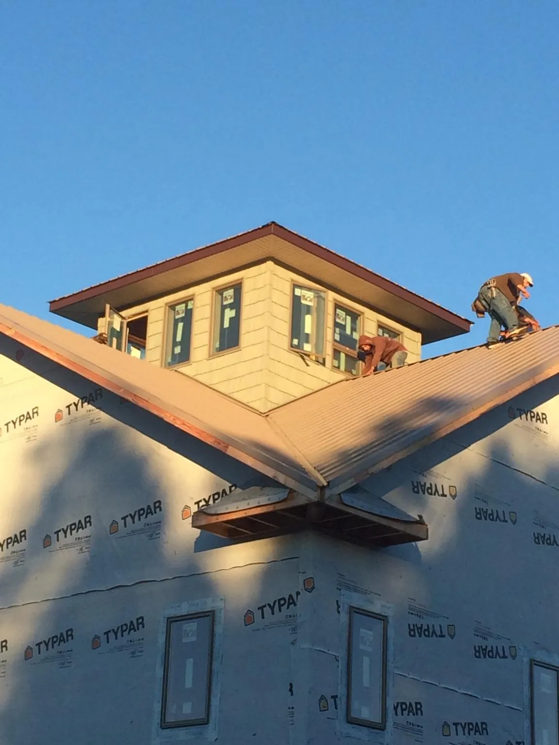 Roofers working around a rooftop cupola on a new metal roof at sunset — Roof Waterproofing in Bridgeport by Roofing Brothers
